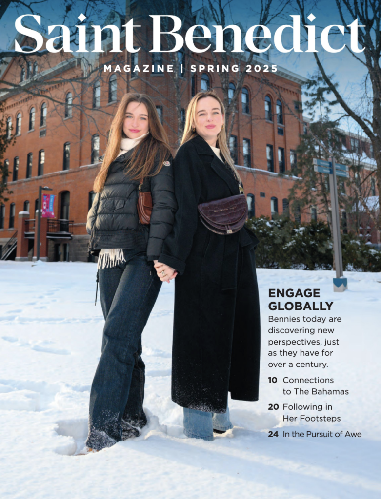 Two young women stand hand in hand in the snow outside a brick building, dressed in winter coats and jeans. The text reads "Saint Benedict Magazine | Spring 2025" with feature articles listed beside them.